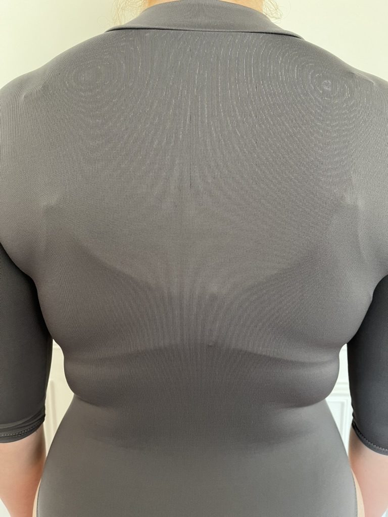 Visible bra straps and bumps under a grey top with an ordinary bra